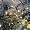 Close-up of LED string lights with warm white bulbs intertwined with frosted branches and greenery. Podgląd zdjęcia produktu