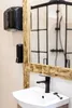 A bathroom sink with a black faucet and a mirror with a wooden frame. Náhled obrázku produktu