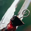 A close-up shot of a skewer with food being held by tongs. Produktbild-Vorschau