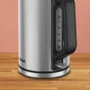 Close-up of a silver electric kettle with a black handle, showing water level markings and the Tefal logo. Voir les images du produit