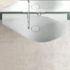 A top-down view of a modern white washbasin with a chrome faucet, set against a tiled wall. Produktbild-Vorschau