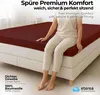 A person sitting on a bed with a fitted sheet. Produktbild-Vorschau