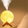 A moon-shaped humidifier lamp with steam and petals rising from the top, resting on a wooden stand. Podgląd zdjęcia produktu