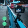 A camera on a tripod attached to a railing on a bridge at night, with blurred traffic lights in the background. Produktbild-Vorschau