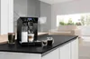 A modern kitchen counter with a DeLonghi coffee machine, coffee beans, and two cups of coffee. Produktbild-Vorschau