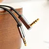 Close-up of two 3.5mm audio cables with gold-plated connectors, resting on a wooden surface. Anteprima dell’immagine prodotto