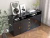 A modern black sideboard with gold handles is displayed in a room with a plant and artwork. Voir les images du produit