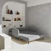 A light gray sofa bed is shown in a minimalist room with a textured gray wall and a built-in white shelf unit. Anteprima dell’immagine prodotto