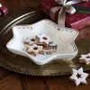 A star-shaped dish filled with star-shaped cookies, placed on a decorative tray next to a wrapped gift. Produktbild-Vorschau