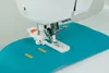 A sewing machine with a buttonhole foot attached, demonstrating how to create buttonholes on a teal fabric. Produktbild-Vorschau
