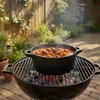A pot of stew is cooking on a grill in a backyard setting. Produktbild-Vorschau
