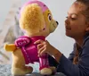 A young girl is interacting with a plush toy dog. Podgląd zdjęcia produktu