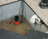 A sump pump submerged in water within a pit, surrounded by gravel and concrete. Anteprima dell’immagine prodotto