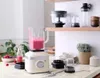 A blender with a pink smoothie and other kitchen accessories on a marble countertop. Náhled obrázku produktu