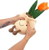 Two hands are squeezing a plush toy of a potted tulip plant. Produktbild-Vorschau