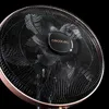 Close-up of a black and copper standing fan against a black background. Podgląd zdjęcia produktu