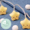 A string of star-shaped LED lights with cute faces, placed on a blue denim-like fabric. Náhľad obrázku produktu