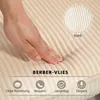 A hand pressing into a beige, corduroy-like fabric, with text overlays highlighting product features. Produktbild-Vorschau