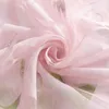 A close-up of pink sheer fabric with a floral or leaf pattern, swirled into a rose shape. Produktbild-Vorschau