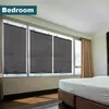 A bedroom with large windows covered by dark roller blinds, and a bed in the foreground. Voir les images du produit
