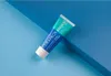 A tube of Curaprox Enzycal toothpaste is placed diagonally on a blue background with geometric lines. Anteprima dell’immagine prodotto