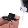 A pink bath bucket with a tablet, wine glass, and a basket attachment. Water is being dispensed from a black container with a white tap into the bucket. Náhled obrázku produktu