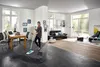 A woman is mopping a floor in a modern living room and dining area. Produktbild-Vorschau