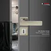 A close-up of a modern door handle and lock mechanism on a gray door, with a glimpse of an interior hallway in the background. Produktbild-Vorschau