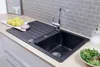 A black kitchen sink with a faucet, lemons, and a bowl of salad on a wooden countertop. Produktbild-Vorschau