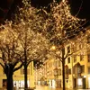 A street decorated with trees wrapped in warm white fairy lights at night. Náhľad obrázku produktu