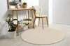 A round, beige rug is placed on a light wooden floor in a room with a console table and a chair. Produktbild-Vorschau
