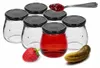 A set of six empty glass jars with black lids, one of which is filled with a red liquid. A strawberry and a pickle are placed in front of the jars. Anteprima dell’immagine prodotto