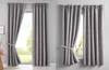 A split image showing two identical sets of grey blackout curtains hanging in front of windows. One set is partially drawn back with a tie-back, revealing a green outdoor scene. The other set is fully closed. Produktbild-Vorschau