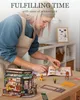 A woman is assembling a miniature bistro model kit on a wooden table. Produktbild-Vorschau