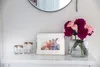 A framed photo and flowers on a shelf. Produktbild-Vorschau