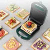 A sandwich maker is open and displaying a sandwich with fruit on top, surrounded by several slices of bread with various toppings. Náhled obrázku produktu