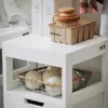A white laundry cabinet with a basket of wool dryer balls on the lower shelf and a brush in a cardboard container on the top shelf. Produktbild-Vorschau