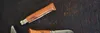 Two Opinel knives are laid out on a dark, textured surface. Podgląd zdjęcia produktu