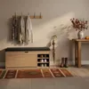 An entryway scene with a shoe cabinet, coats, a scarf, an umbrella, boots, and a table with autumn decor. Produktbild-Vorschau