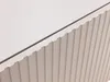 A close-up view of a white cabinet with a ribbed texture on the right side and a smooth surface on the left, separated by a dark line. Náhled obrázku produktu