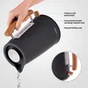 A hand is pouring water from a black electric kettle with wooden accents. Voir les images du produit