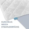 A close-up of a white quilted blanket with a blue tag. Náhled obrázku produktu