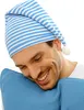 A man wearing a striped sleeping cap is resting his head on a blue pillow. Produktbild-Vorschau