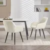 Two cream-colored dining chairs with black legs are placed around a dining table in a well-lit room. Produktbild-Vorschau