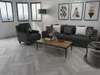 A modern living room with a sofa, armchair, coffee table, and artwork on the wall. Produktbild-Vorschau
