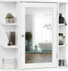 A white bathroom cabinet with a mirror is shown against a white background. The cabinet has shelves on the sides and a mirrored door in the center. The reflection in the mirror shows a modern bathroom interior with a bathtub and pendant lights. Produktbild-Vorschau