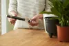 A person is holding a black watering insert next to a plant pot. Náhled obrázku produktu