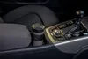 A travel mug sits in a car's cup holder next to the gear shift. Podgląd zdjęcia produktu