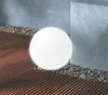 A white spherical solar lamp sits on a wooden deck surrounded by gravel, next to a concrete structure. Produktbild-Vorschau