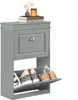 A gray shoe cabinet with two flip-out drawers is displayed against a white background. The top of the cabinet has decorative items and books. Produktbild-Vorschau